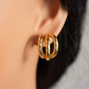 Close-up of triple layered 18k gold twisted hoop earrings showing spiral texture and luster