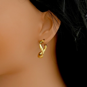 Detailed view of twisted gold irregular geometric earrings on a model ear