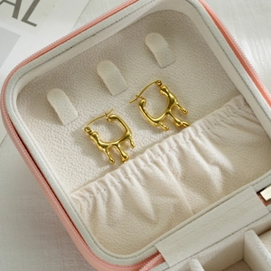 Detailed shot of golden twisted hoop earrings inside a pink jewelry storage box