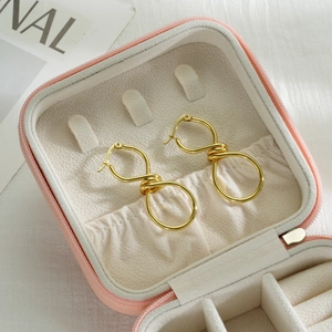 Close-up of golden irregular twisted hoop earrings in a pink velvet jewelry box
