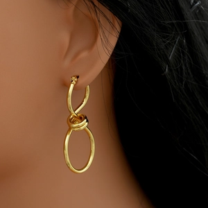 Close-up of gold irregular twisted knot earrings on ear showing high polished metal finish