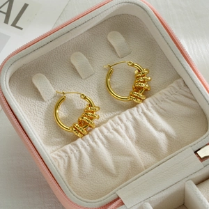 Golden irregular twist hoop earrings with spiral texture displayed in a pink jewelry box