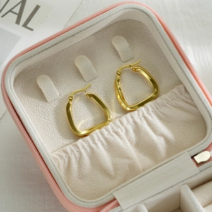 Close-up of golden irregular geometric hoop earrings inside a pink jewelry box