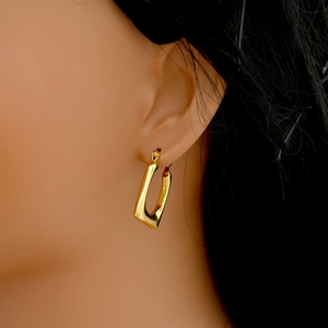 Close-up of gold irregular geometric earrings worn on ear showing polished finish