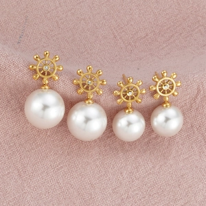 Detailed view of 18k gold plated nautical helm earrings with elegant hanging white pearls