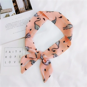Detail of pink flamingo print silk scarf tied in a bow on a soft white fabric background