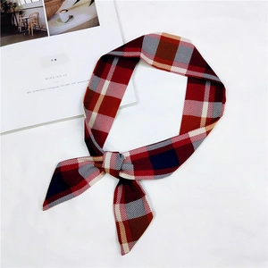 Macro detail of red plaid pattern silk scarf tied in a bow against a white background