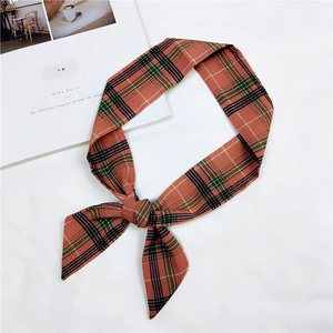 Detail of a vintage orange plaid silk scarf tied in a bow on a lifestyle magazine