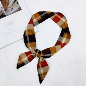 Close-up of a plaid silk ribbon tied in a bow on a white background with a magazine