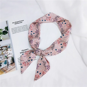 Detail of pink floral silk scarf tied in a bow on a white textured fabric background