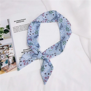 Detail of light blue floral chiffon scarf tied as a hair tie on white fabric