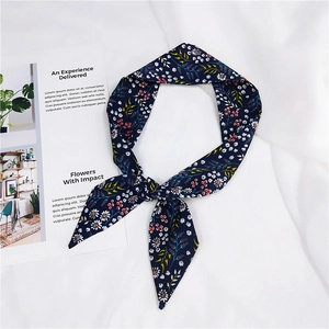 Detailed close-up of a floral print chiffon scarf tied in a bow on a soft white background