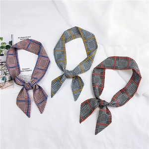 Flat lay of three checkered skinny scarves in red, yellow, and blue patterns on white fabric