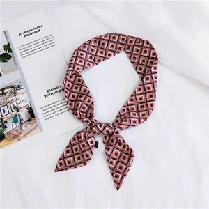 Detailed view of dusty pink silk scarf with geometric patterns tied on white fabric