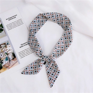 Detail of geometric pattern silk scarf tied in a bow on elegant white fabric