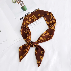Detailed view of dark brown floral silk scarf tied in a bow on a magazine background