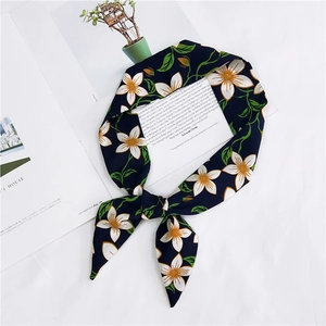 Close-up of navy blue floral silk scarf tied in a knot on a minimalist magazine