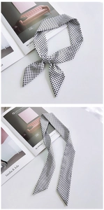 Close-up of black and white polka dot silk scarf tied as a bow on a magazine
