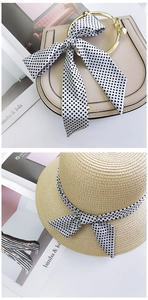 Polka dot silk scarf styled on beige handbag handle and straw sun hat for vacation