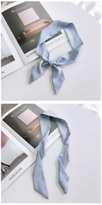 Detail of light blue polka dot silk scarf tied in a bow on a stylish magazine