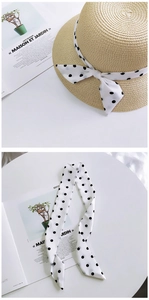Detail of a beige straw hat with a detachable black and white polka dot silk scarf tie