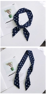 Close-up of navy blue polka dot silk scarf tied on a white surface with magazine