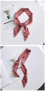 Close-up of a red and white polka dot silk scarf tied as a hair ribbon on a magazine