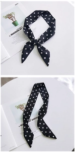 Detailed view of polka dot satin skinny scarf tied as a bow on a fashion magazine