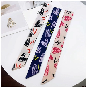 Detailed view of three long twilly scarves with heart graffiti patterns on a table