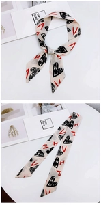 Detail of a silky twilly scarf featuring black hand-drawn hearts and red letter prints