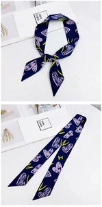 Close-up of heart print navy twilly silk scarf tied on a minimalist white display