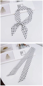Close-up of black and white polka dot silk scarf tied and flat on a white table