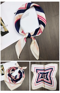 Detail view of a striped silk square scarf with geometric patterns on a wooden background