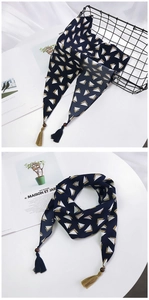 Détail d'un foulard en soie bleu marine avec imprimé géométrique, glands et perles