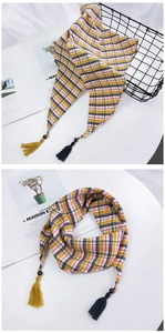 Détail d'un foulard triangle à carreaux avec glands et ornements en perles de bois