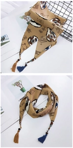 Détail d'un foulard en satin kaki avec imprimés écureuils et glands décoratifs