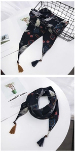 Détail d'un foulard bohème avec perles en bois, plumes et pompons sur fond minimaliste