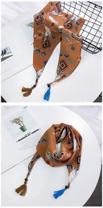Détail d'un foulard bohème avec imprimé plumes, pompons et perles en bois sur fond blanc