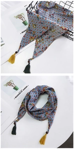 Détail du foulard en soie à motif paisley avec perles en bois et pompons colorés