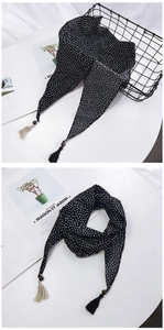 Détail d'un foulard en soie à pois noirs avec pompons bicolores et finition satinée