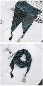 Détail d'un foulard vert foncé à pois avec perles en bois et pompons à franges bicolores