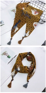 Détail d'un foulard en soie gingembre avec imprimés animaux, perles et glands