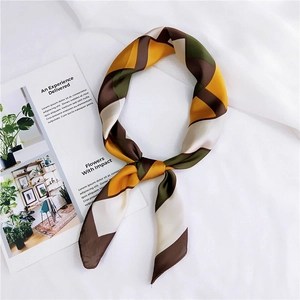 Detail of geometric patterned silk scarf in mustard, olive, and brown on white fabric