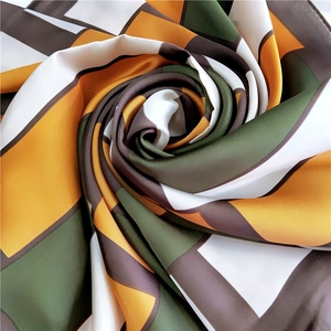Detail of satin square scarf with geometric blocks in green, yellow and brown colors