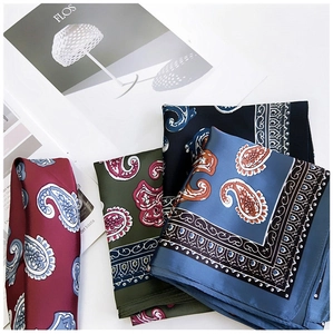 Macro detail of silk-like paisley square scarves in burgundy, olive, and navy colors