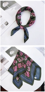 Detailed view of dark green paisley silk scarf with vintage patterns on a magazine background