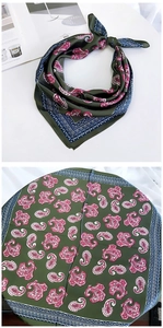 Close-up of square silk scarf with green paisley patterns and satin texture displayed on a table