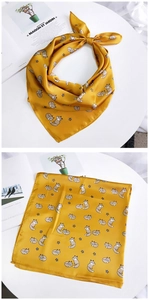 Détail d'un foulard en soie jaune avec motifs renard et étoiles, noué et posé à plat