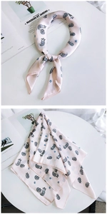 Détail d'un foulard en soie rose avec motifs de renards gris et texture satinée
