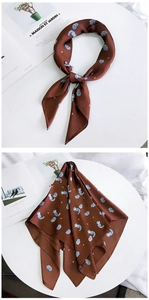Détail d'un foulard en soie marron foncé avec renards bleus et étoiles jaunes sur magazine